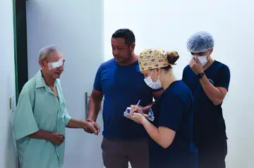 Paciente após cirurgia oftalmológica com equipe médica