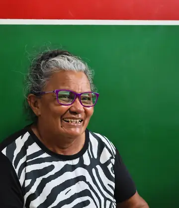 Mulher ribeirinha sorrindo com óculos novos de armação roxa